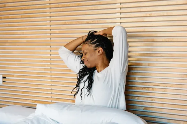 a woman stretching in bed after waking up
